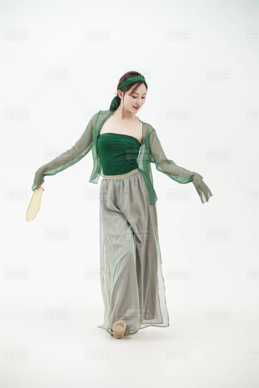 身穿青色古典舞蹈服裝手拿蒲扇跳舞的少女