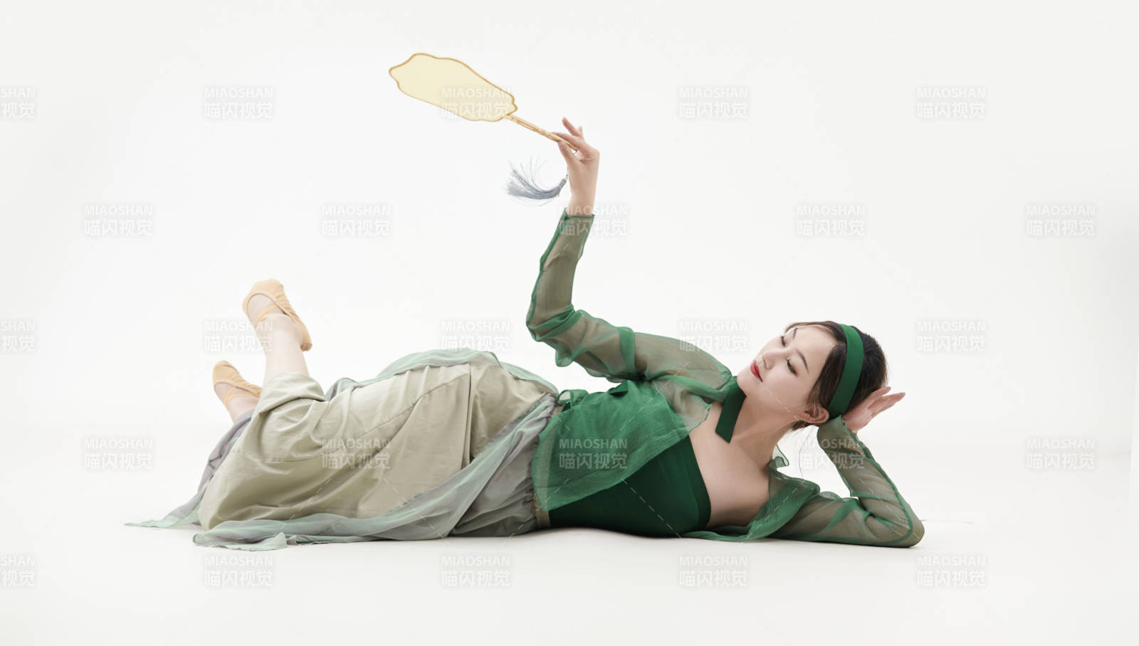 身穿青色古典舞蹈服裝手拿蒲扇跳舞的少女