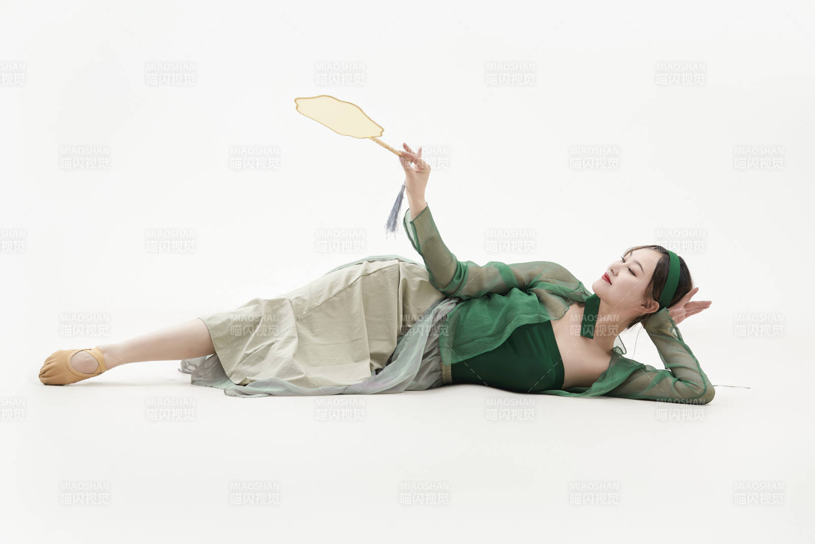 身穿青色古典舞蹈服裝手拿蒲扇跳舞的少女