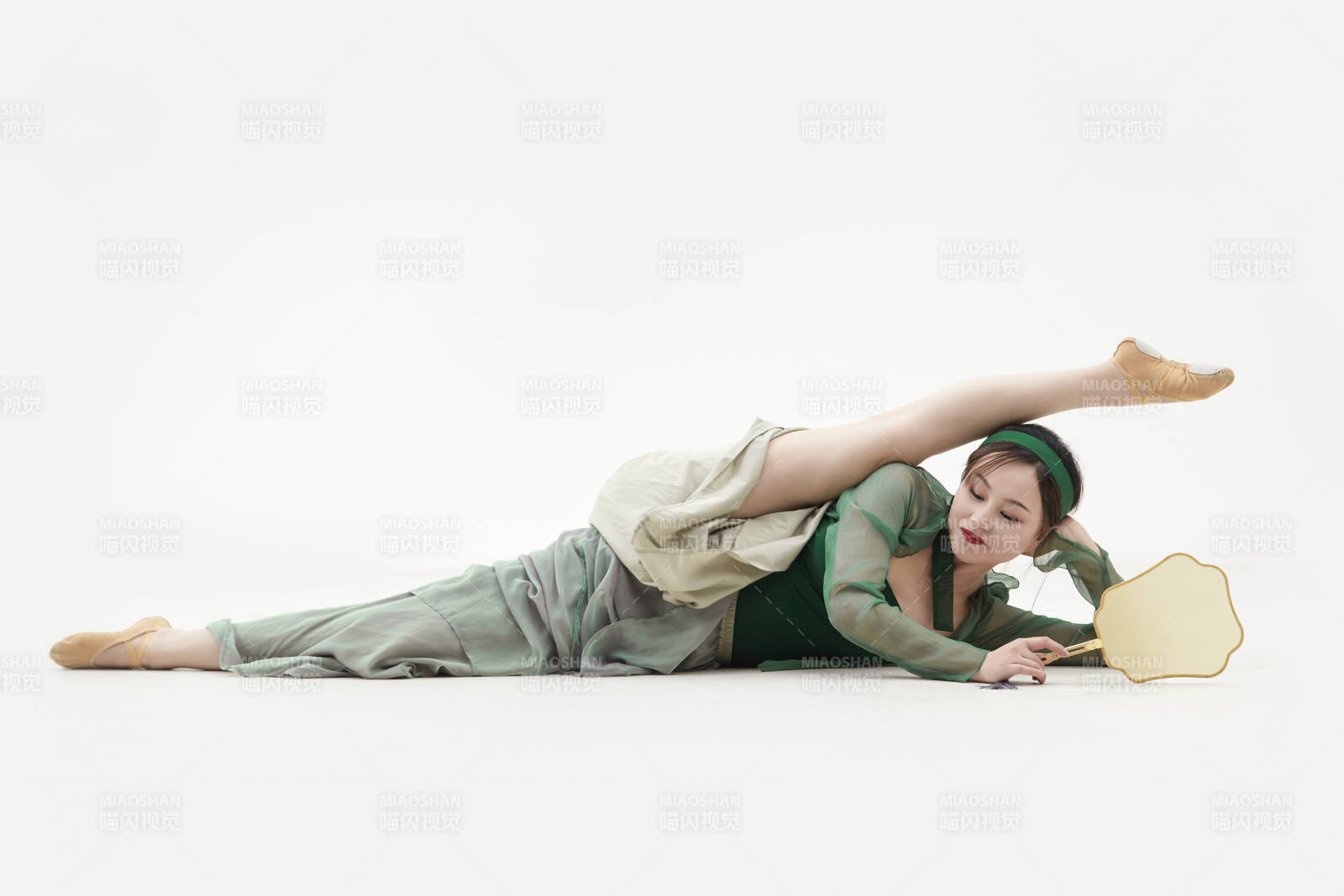 身穿青色古典舞蹈服裝手拿蒲扇跳舞的少女