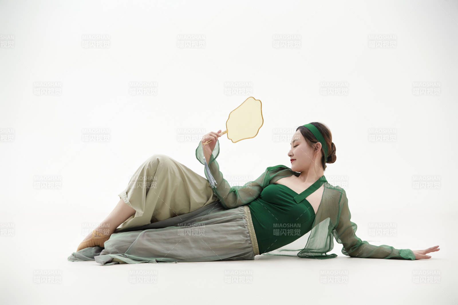 身穿青色古典舞蹈服裝手拿蒲扇跳舞的少女