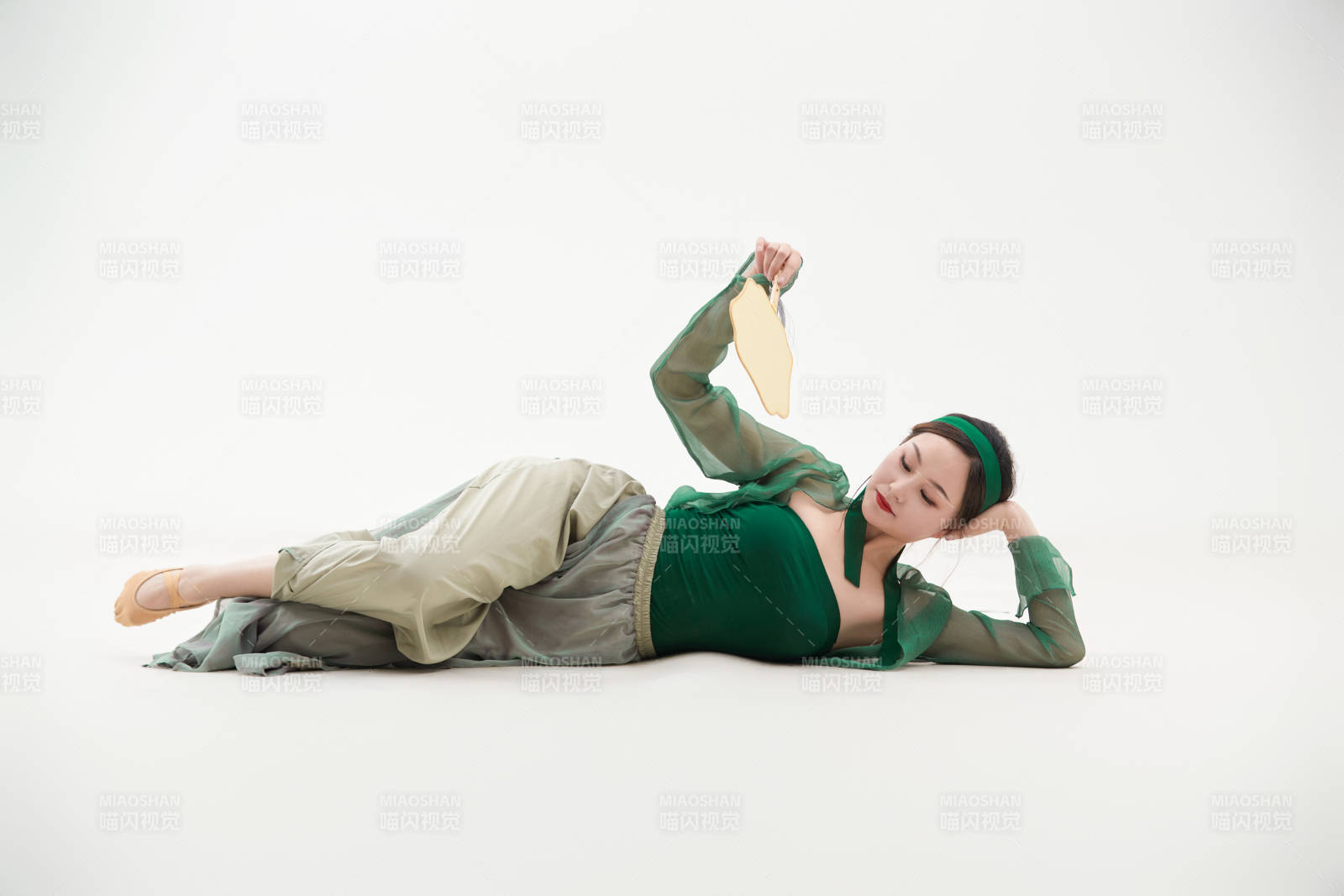 身穿青色古典舞蹈服裝手拿蒲扇跳舞的少女