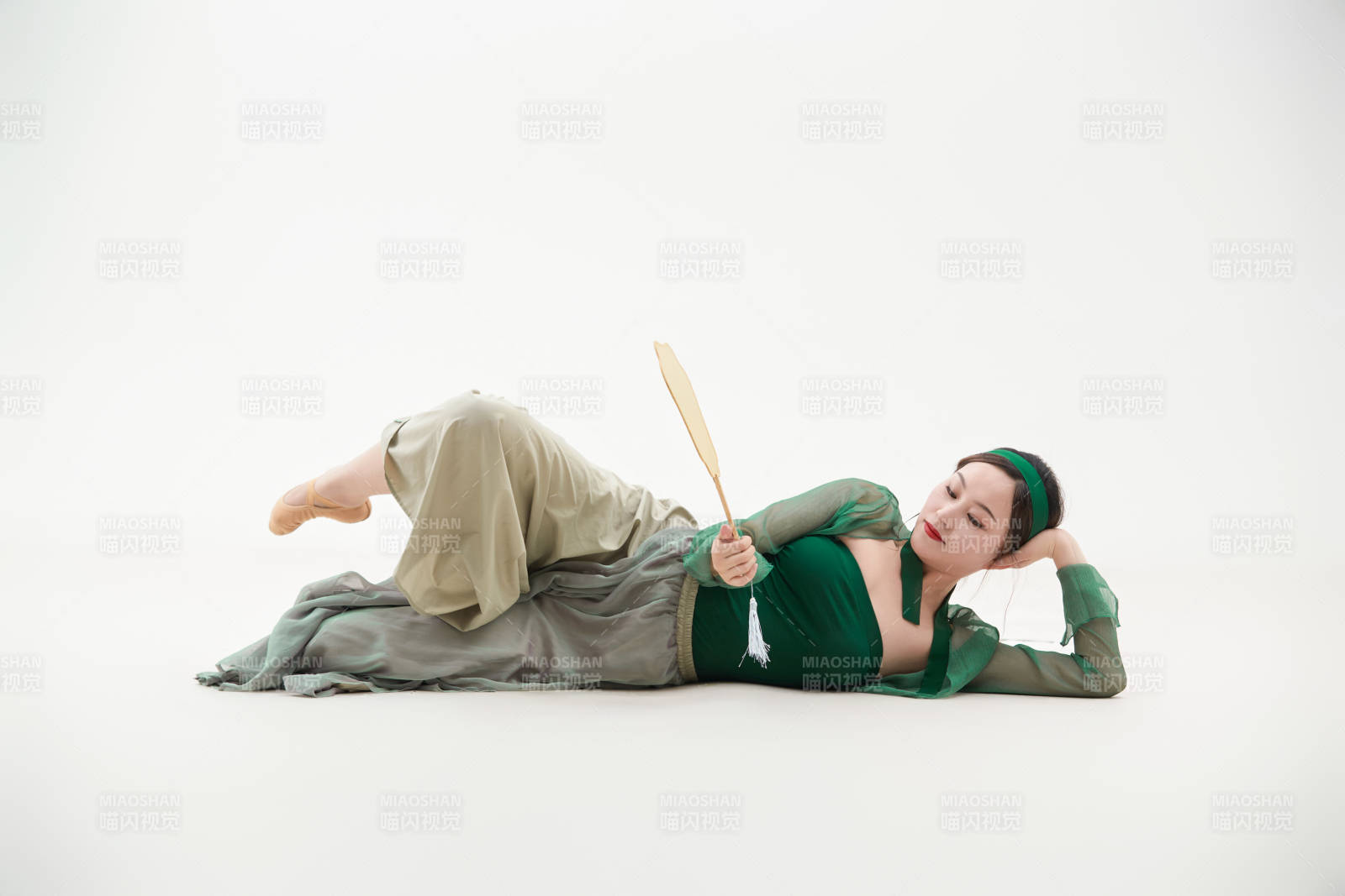 身穿青色古典舞蹈服裝手拿蒲扇跳舞的少女