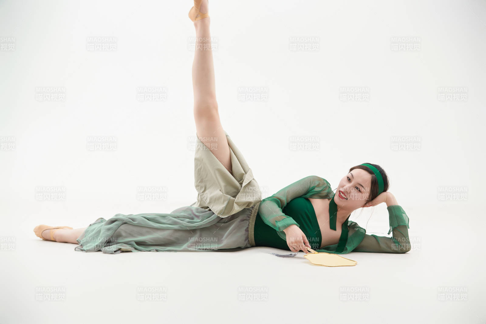 身穿青色古典舞蹈服裝手拿蒲扇跳舞的少女