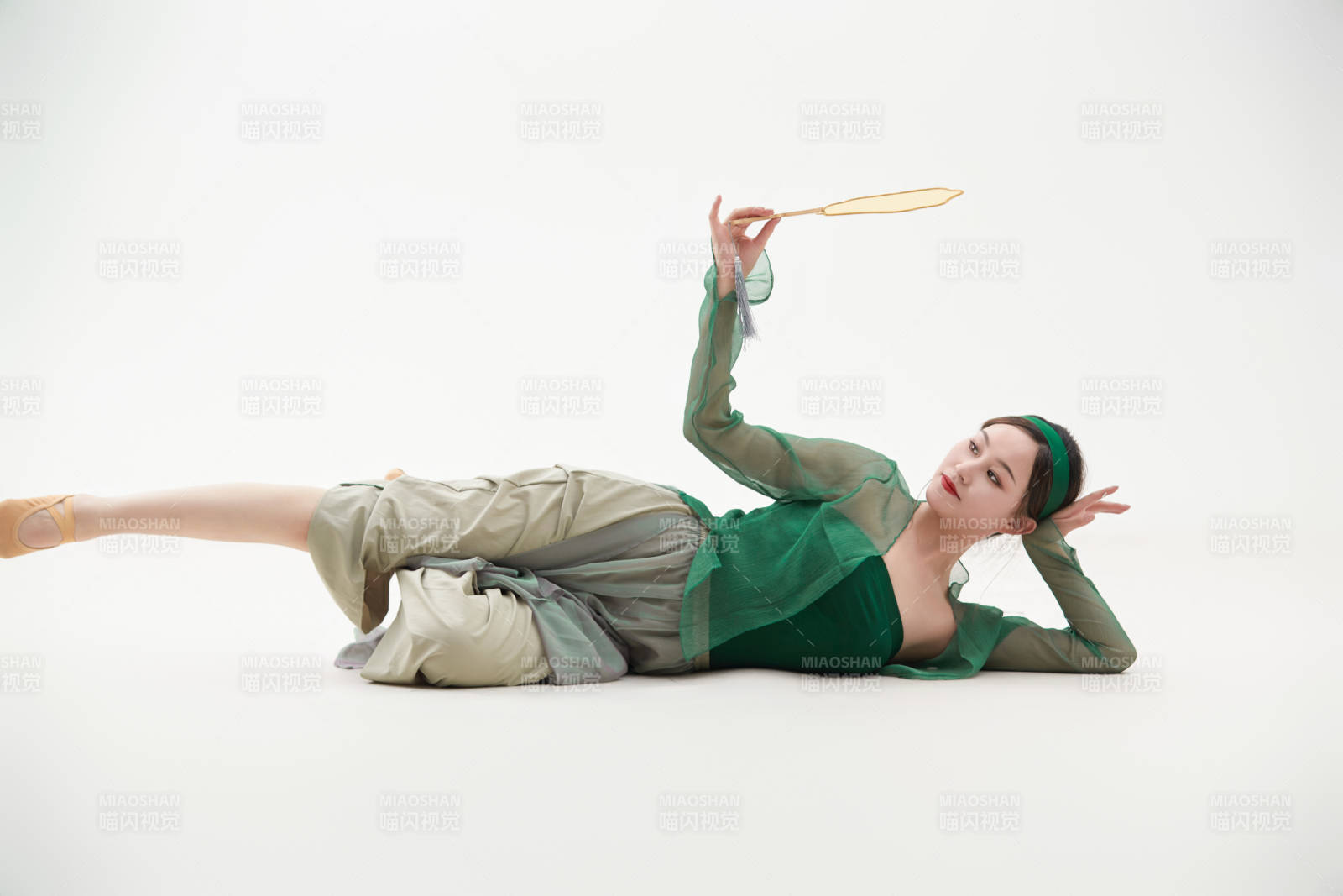 身穿青色古典舞蹈服裝手拿蒲扇跳舞的少女