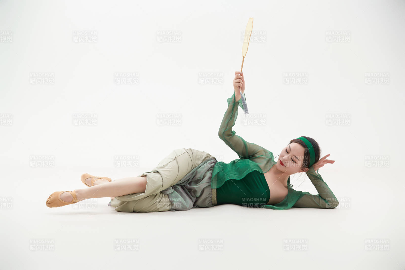 身穿青色古典舞蹈服裝手拿蒲扇跳舞的少女