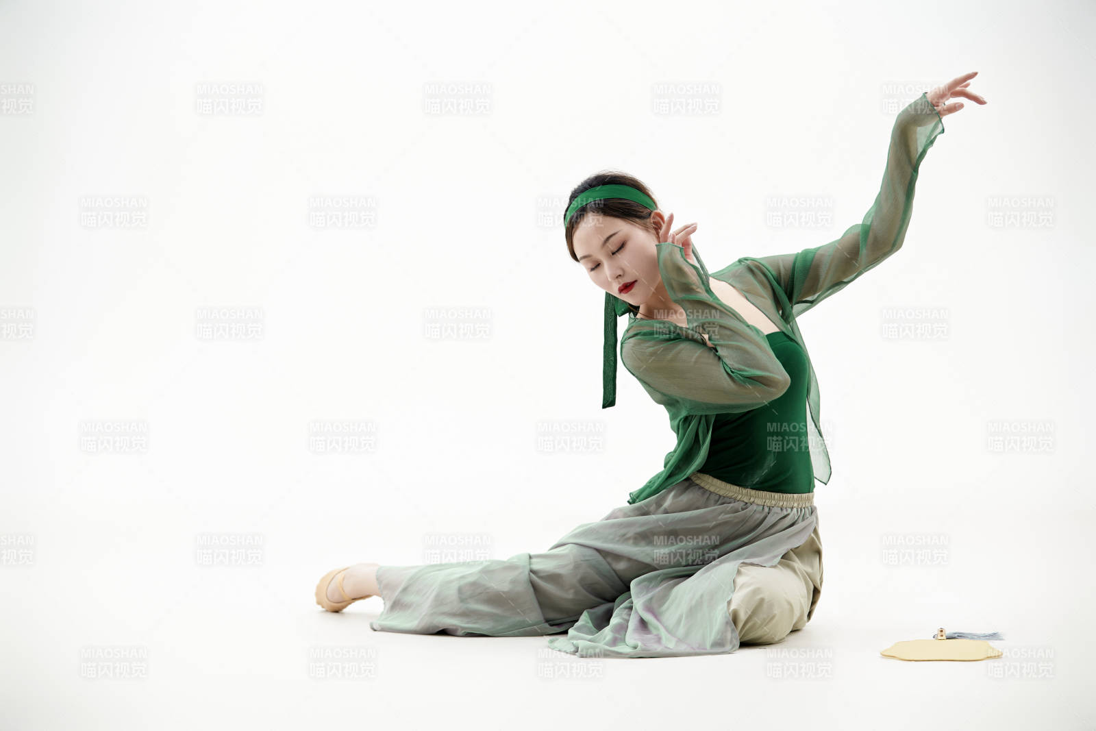 身穿青色古典舞蹈服裝手拿蒲扇跳舞的少女