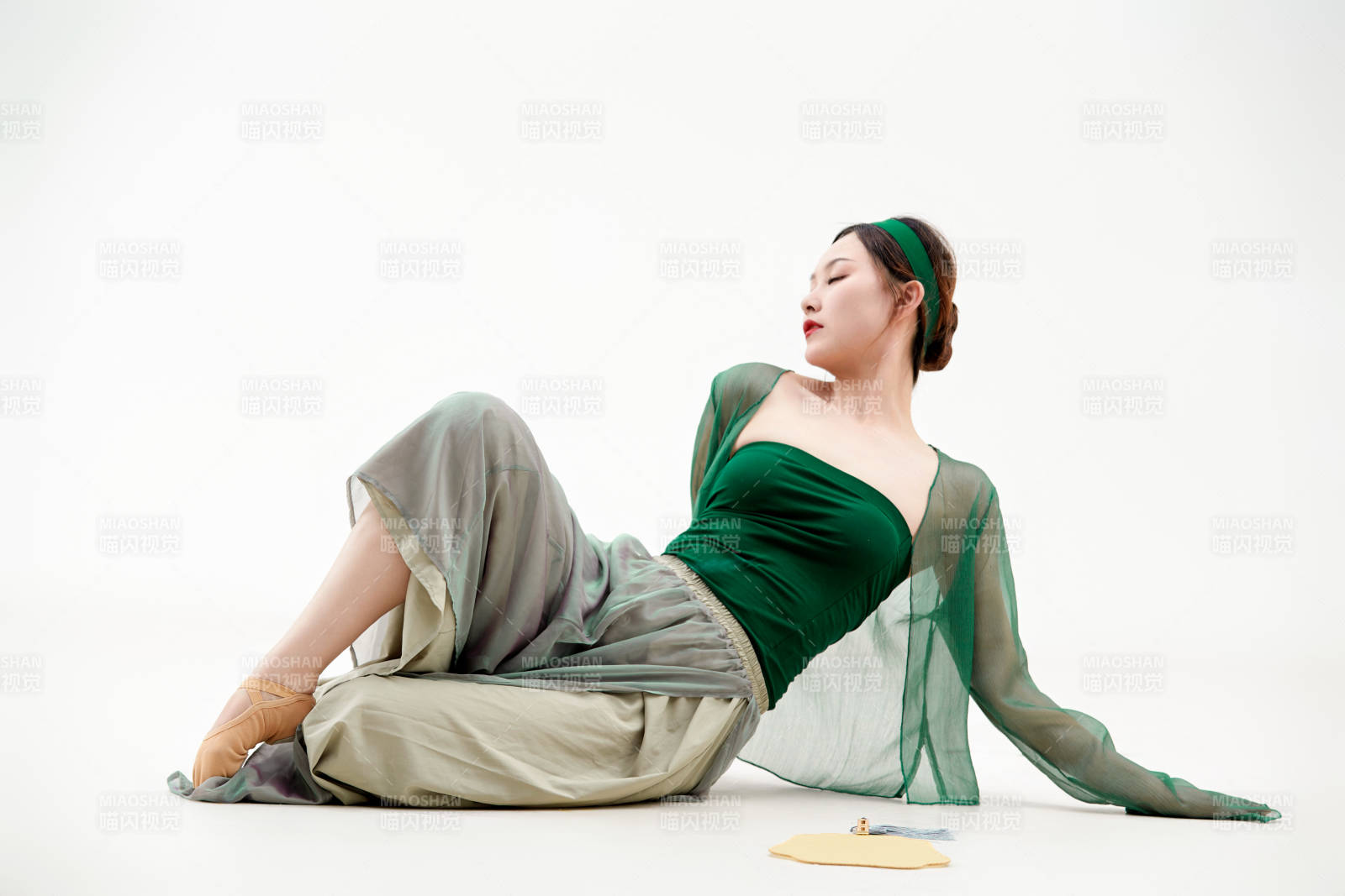 身穿青色古典舞蹈服裝手拿蒲扇跳舞的少女