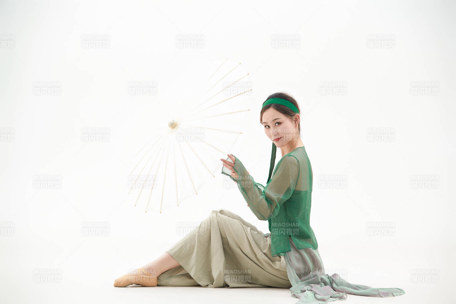 身穿青色古典舞蹈服裝手拿蒲扇跳舞的少女