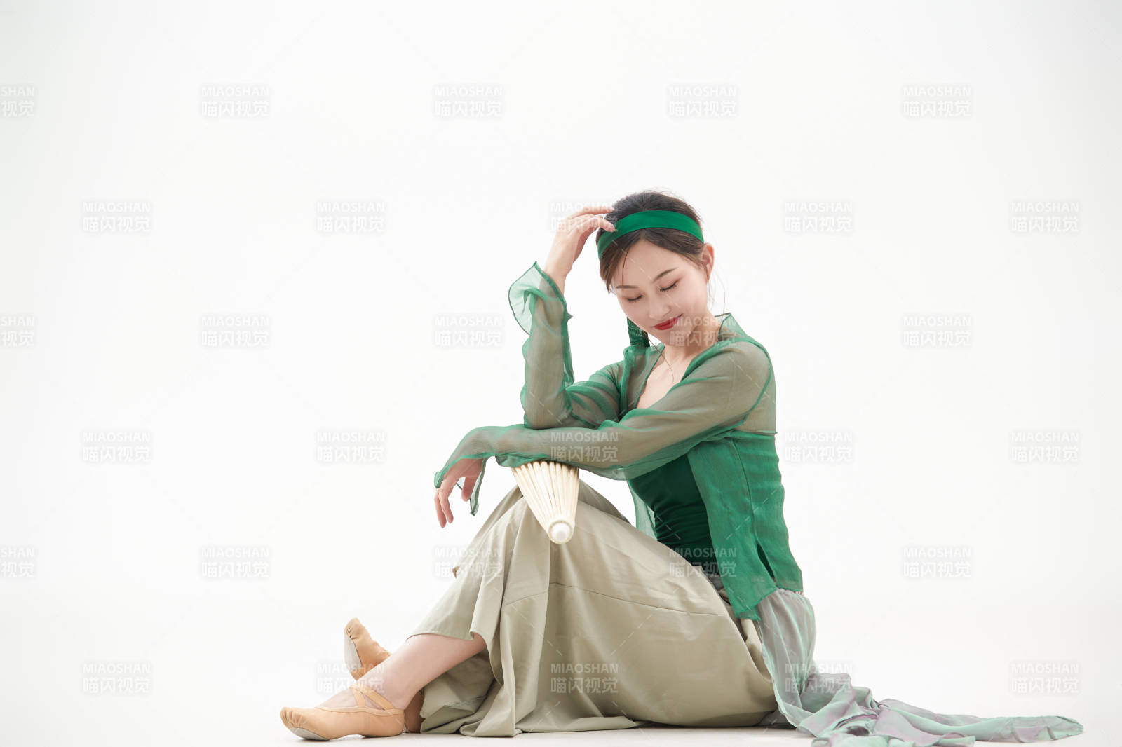 身穿青色古典舞蹈服裝手拿蒲扇跳舞的少女