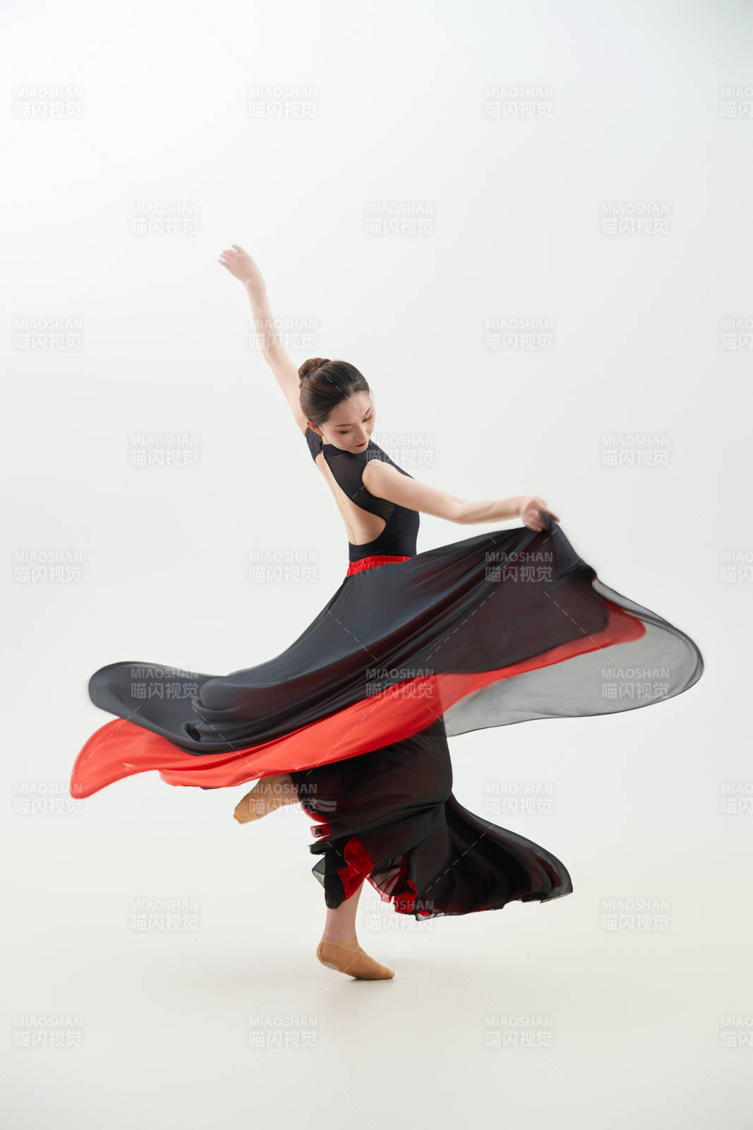 身穿紅黑相間的舞蹈長裙翩翩起舞的少女