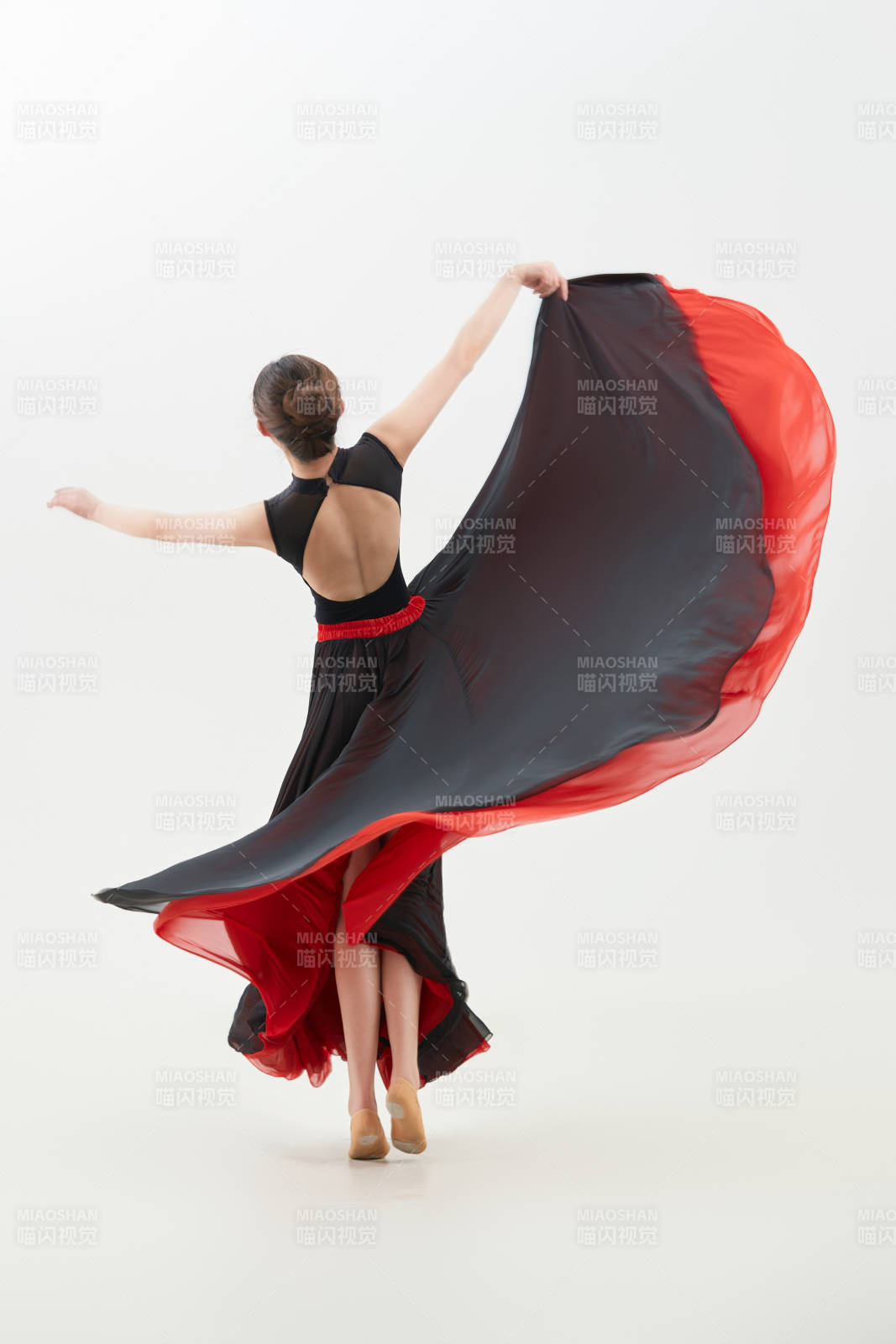 身穿紅黑相間的舞蹈長裙翩翩起舞的少女