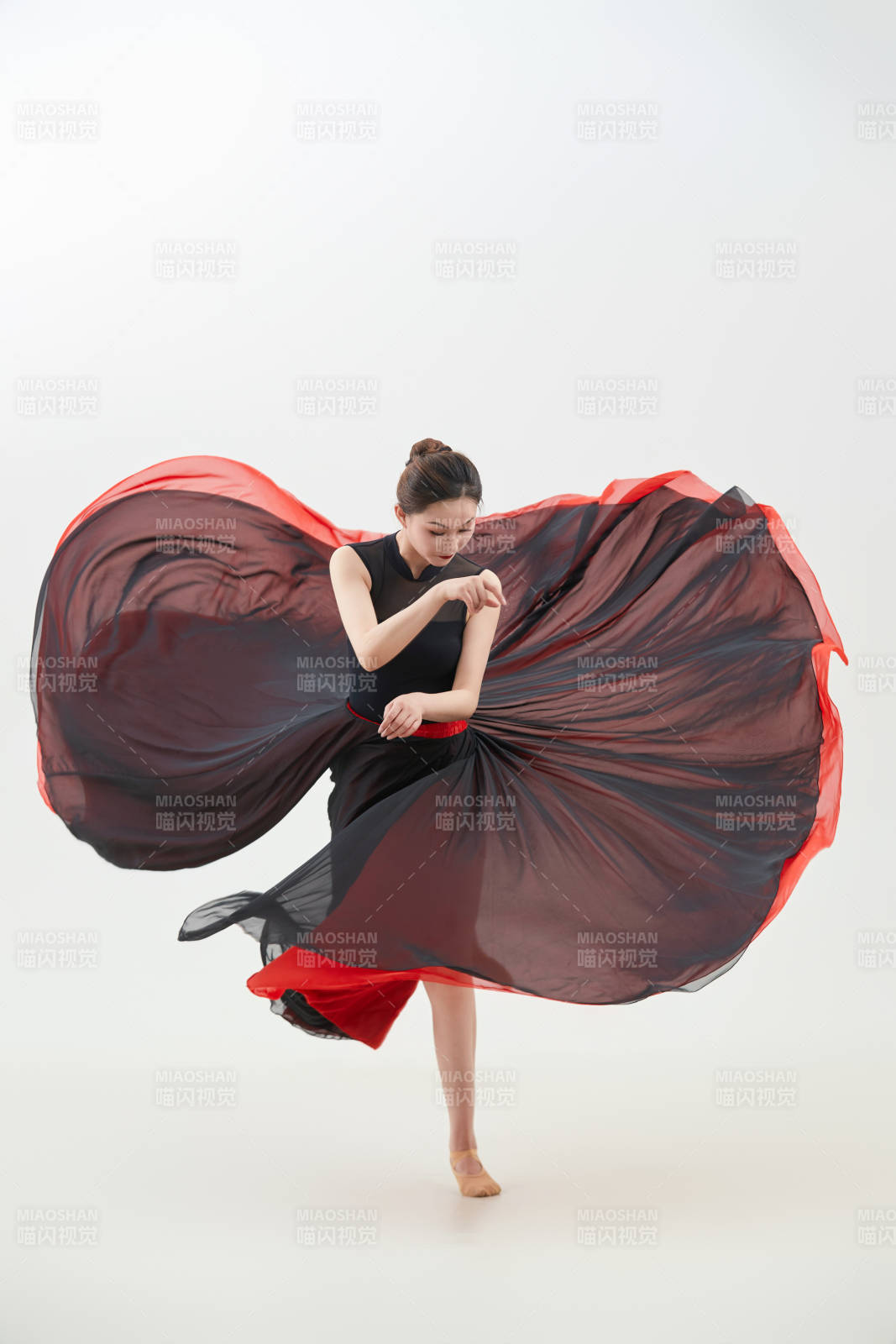 身穿紅黑相間的舞蹈長裙翩翩起舞的少女