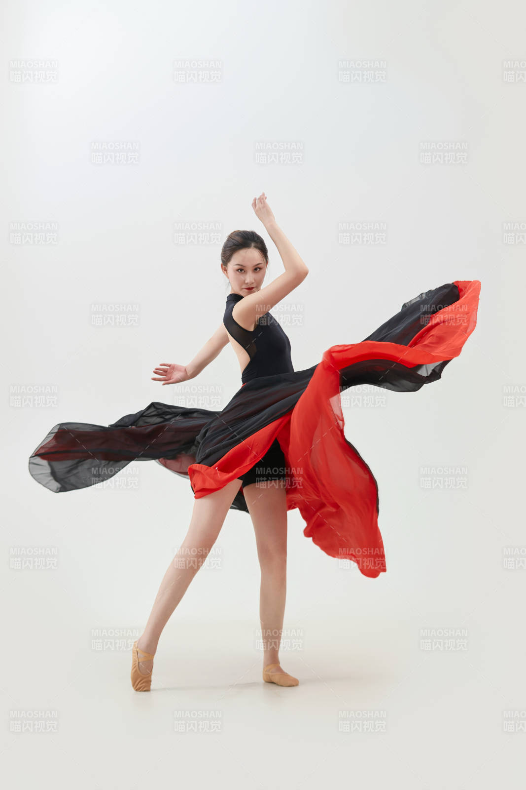 身穿紅黑相間的舞蹈長裙翩翩起舞的少女