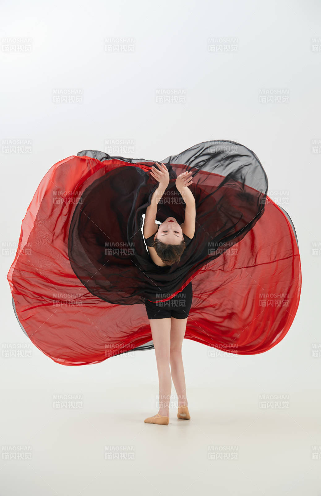 身穿紅黑相間的舞蹈長裙翩翩起舞的少女