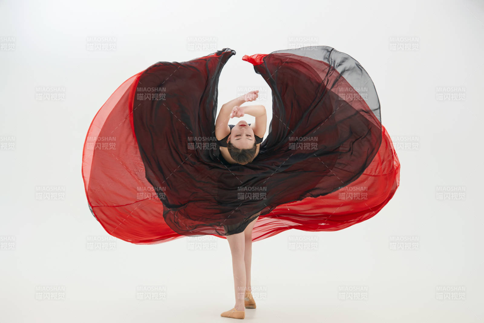 身穿紅黑相間的舞蹈長裙翩翩起舞的少女