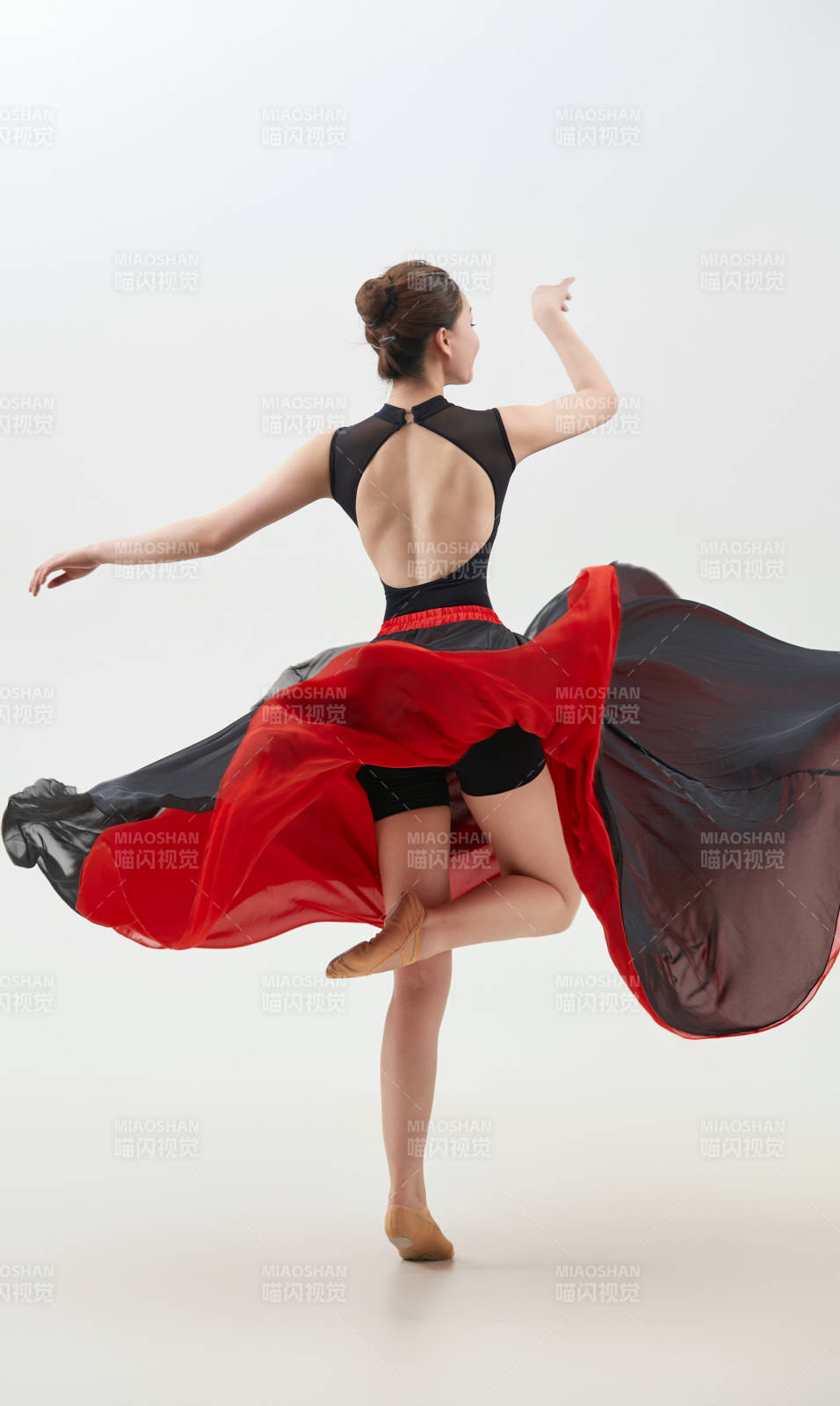 身穿紅黑相間的舞蹈長裙翩翩起舞的少女