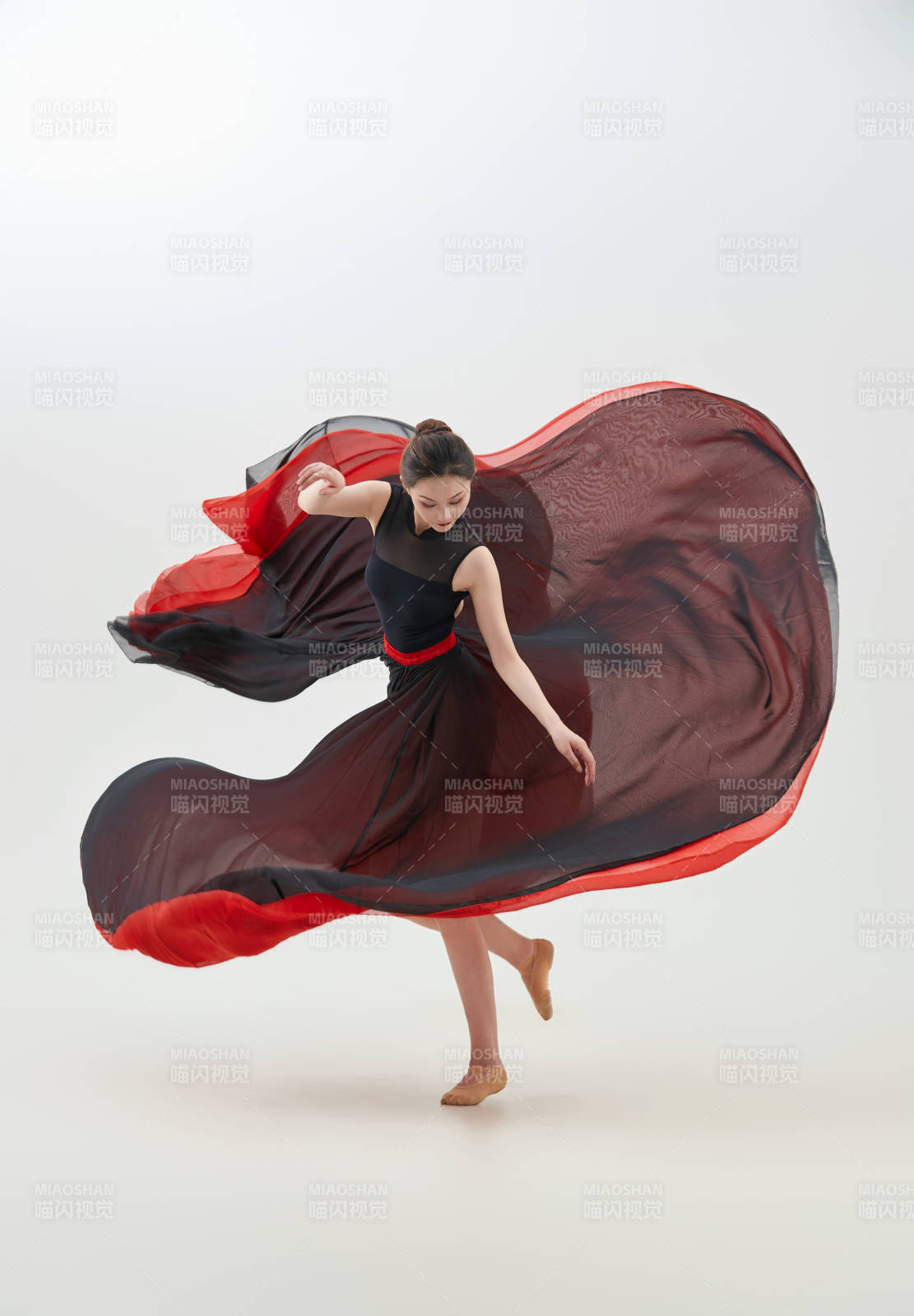 身穿紅黑相間的舞蹈長裙翩翩起舞的少女