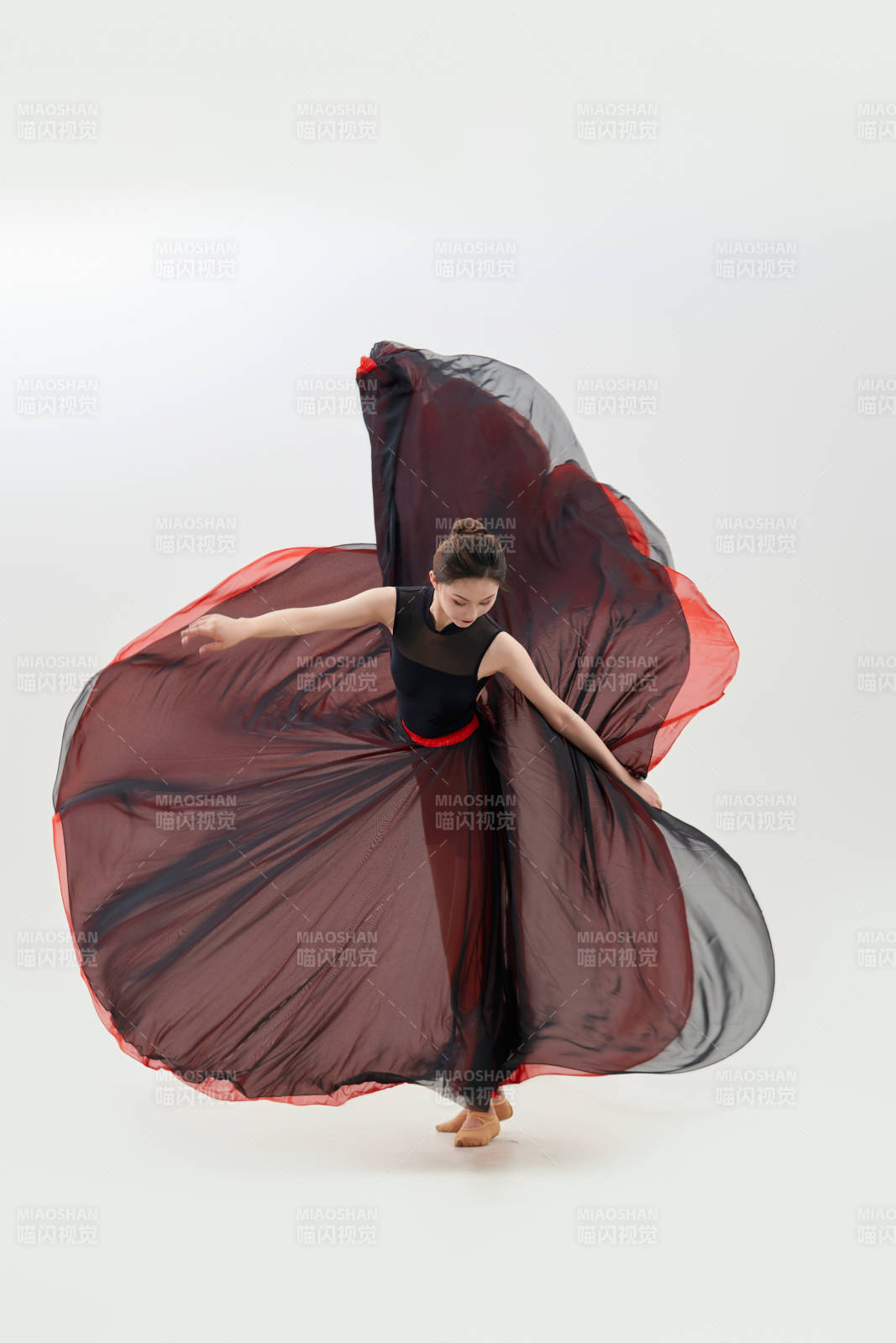 身穿紅黑相間的舞蹈長裙翩翩起舞的少女