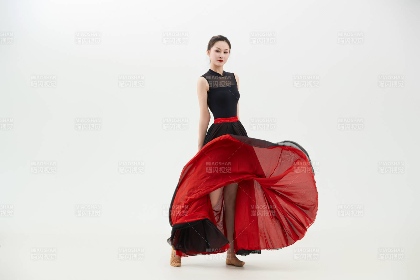 身穿紅黑相間的舞蹈長裙翩翩起舞的少女