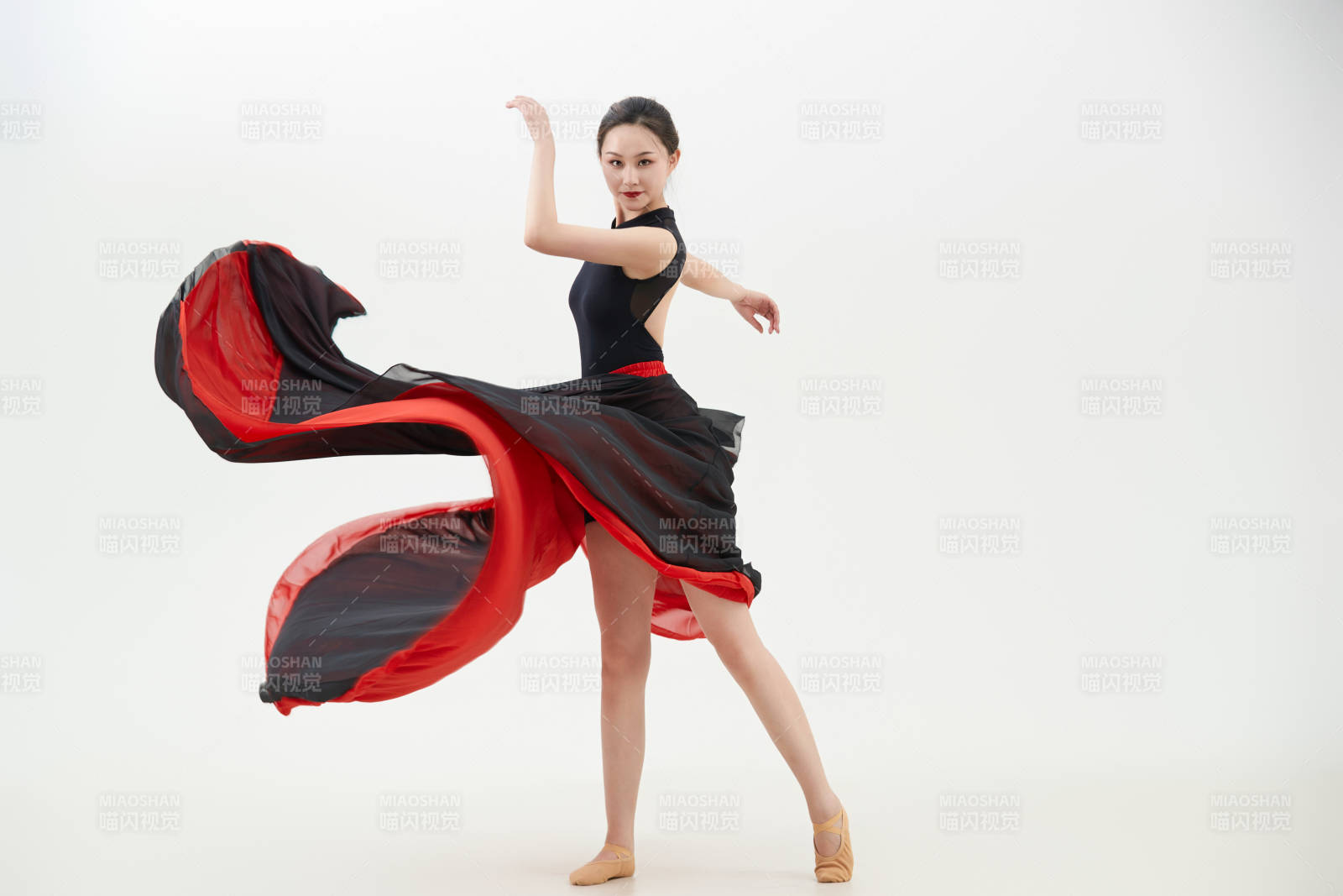 身穿紅黑相間的舞蹈長裙翩翩起舞的少女