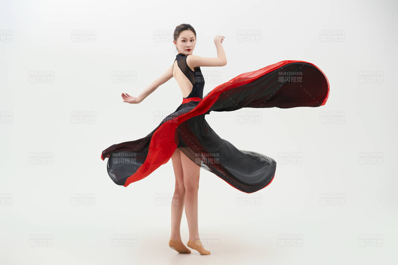 身穿紅黑相間的舞蹈長裙翩翩起舞的少女