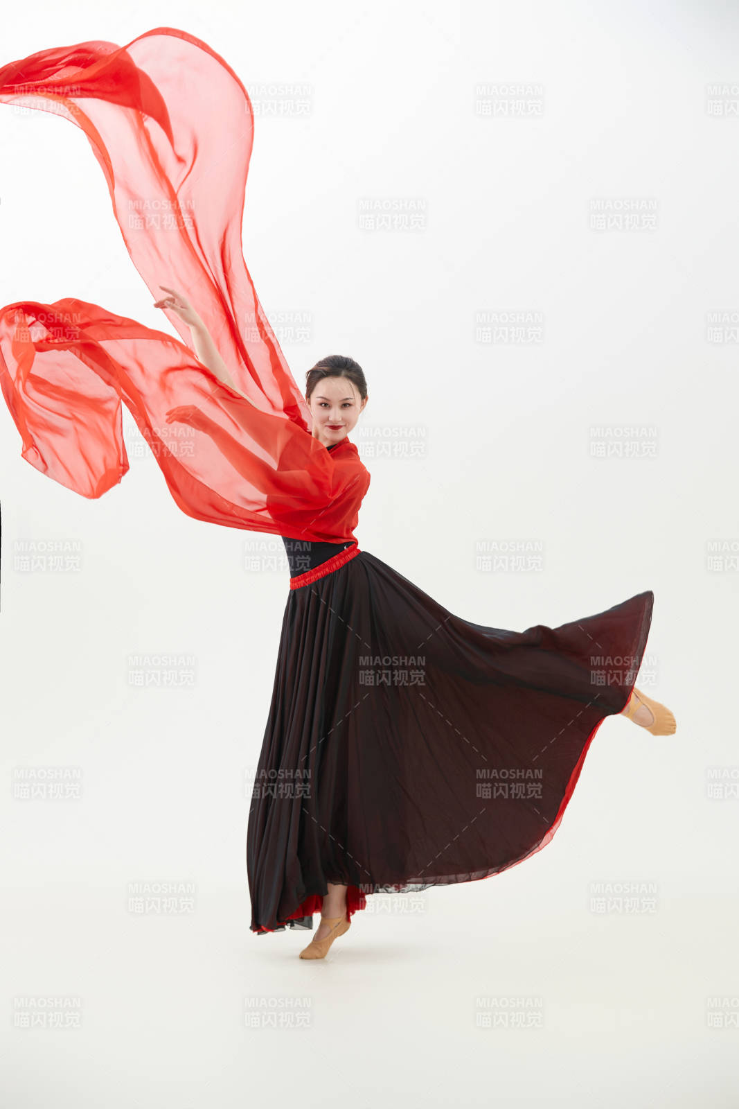 身穿紅黑相間的舞蹈長裙翩翩起舞的少女