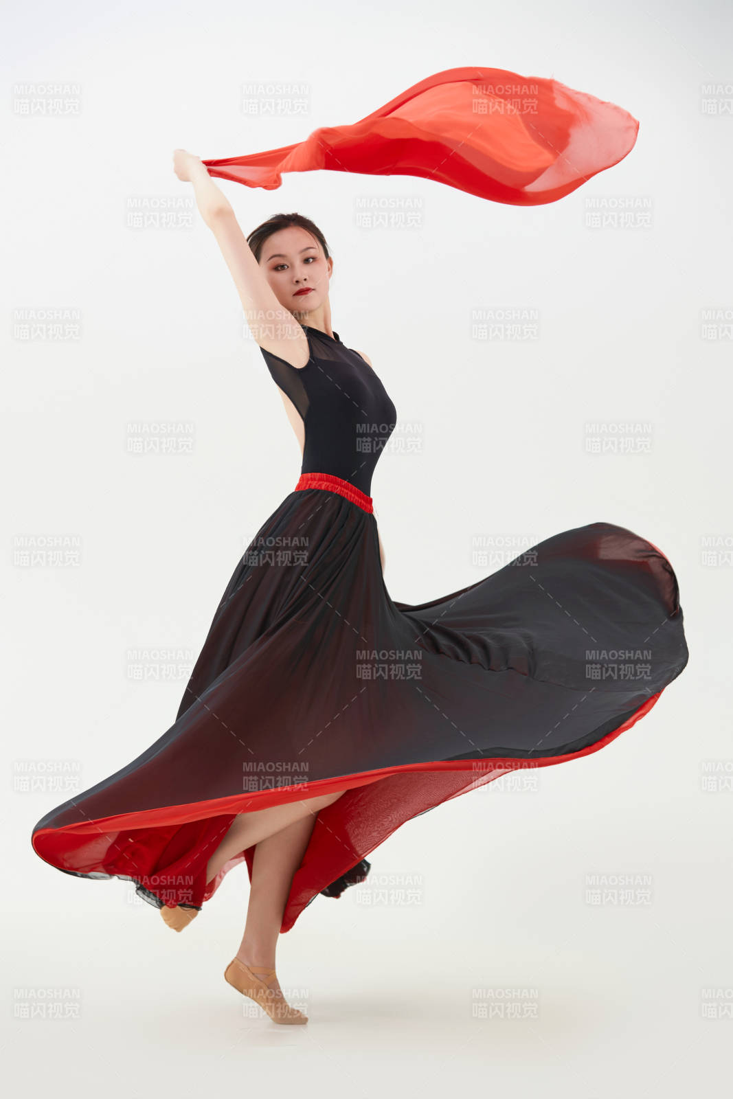 身穿紅黑相間的舞蹈長裙翩翩起舞的少女