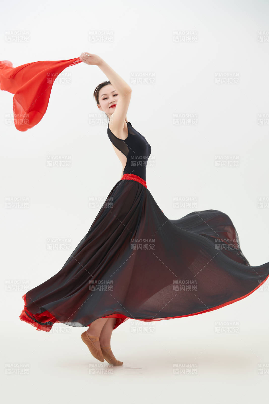 身穿紅黑相間的舞蹈長裙翩翩起舞的少女