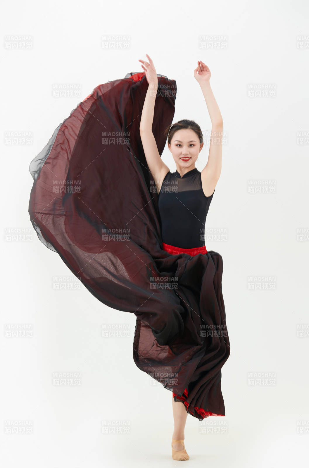 身穿紅黑相間的舞蹈長裙翩翩起舞的少女