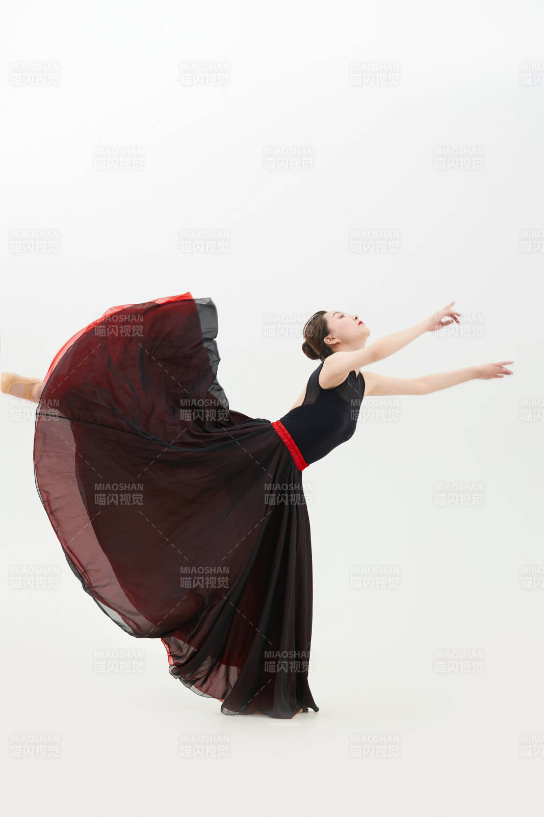 身穿紅黑相間的舞蹈長裙翩翩起舞的少女