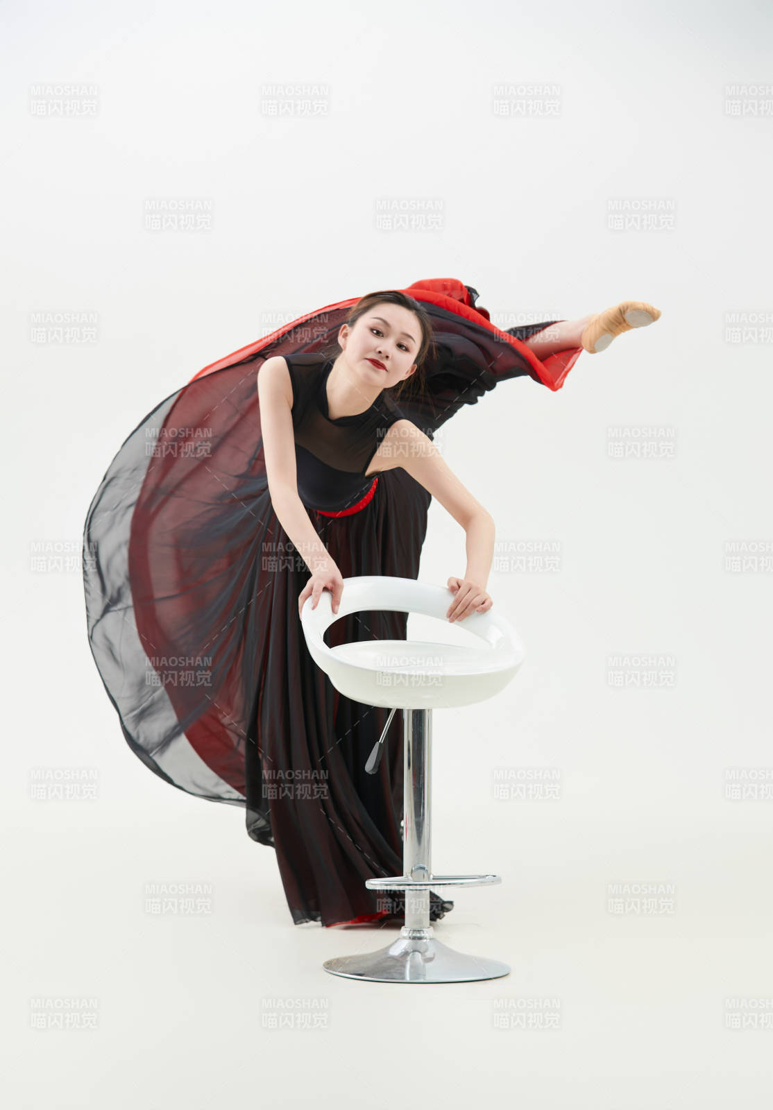 身穿紅黑相間的舞蹈長裙翩翩起舞的少女