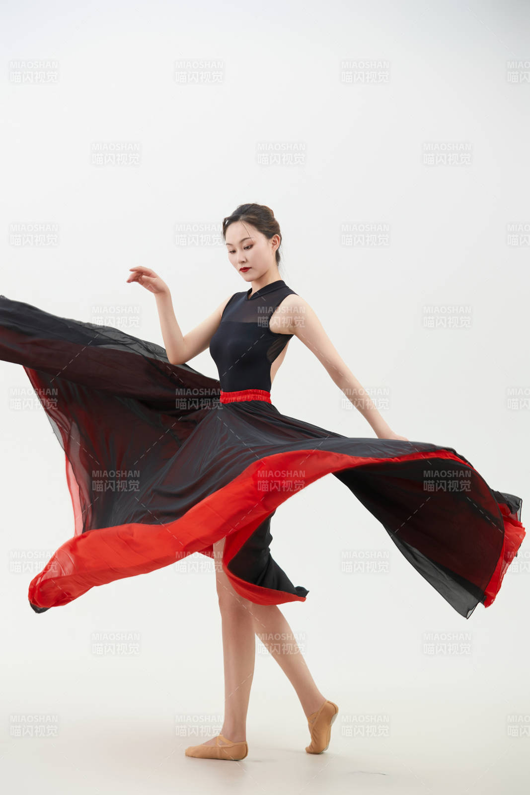 身穿紅黑相間的舞蹈長裙翩翩起舞的少女