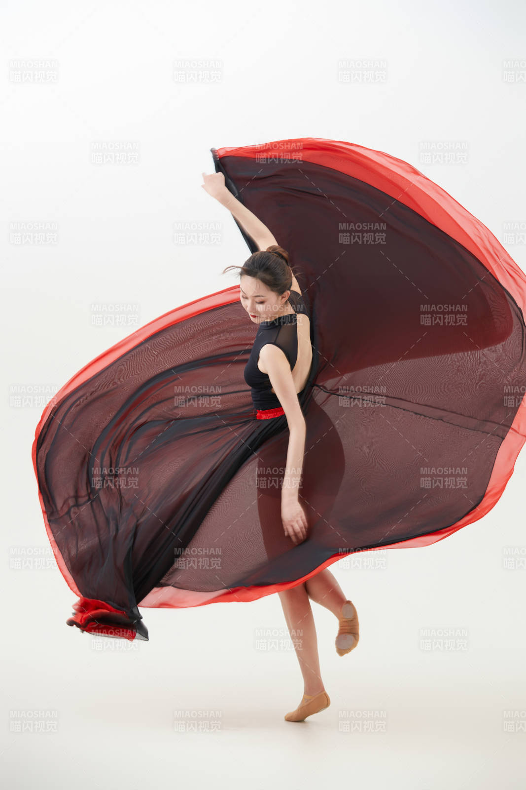 身穿紅黑相間的舞蹈長裙翩翩起舞的少女