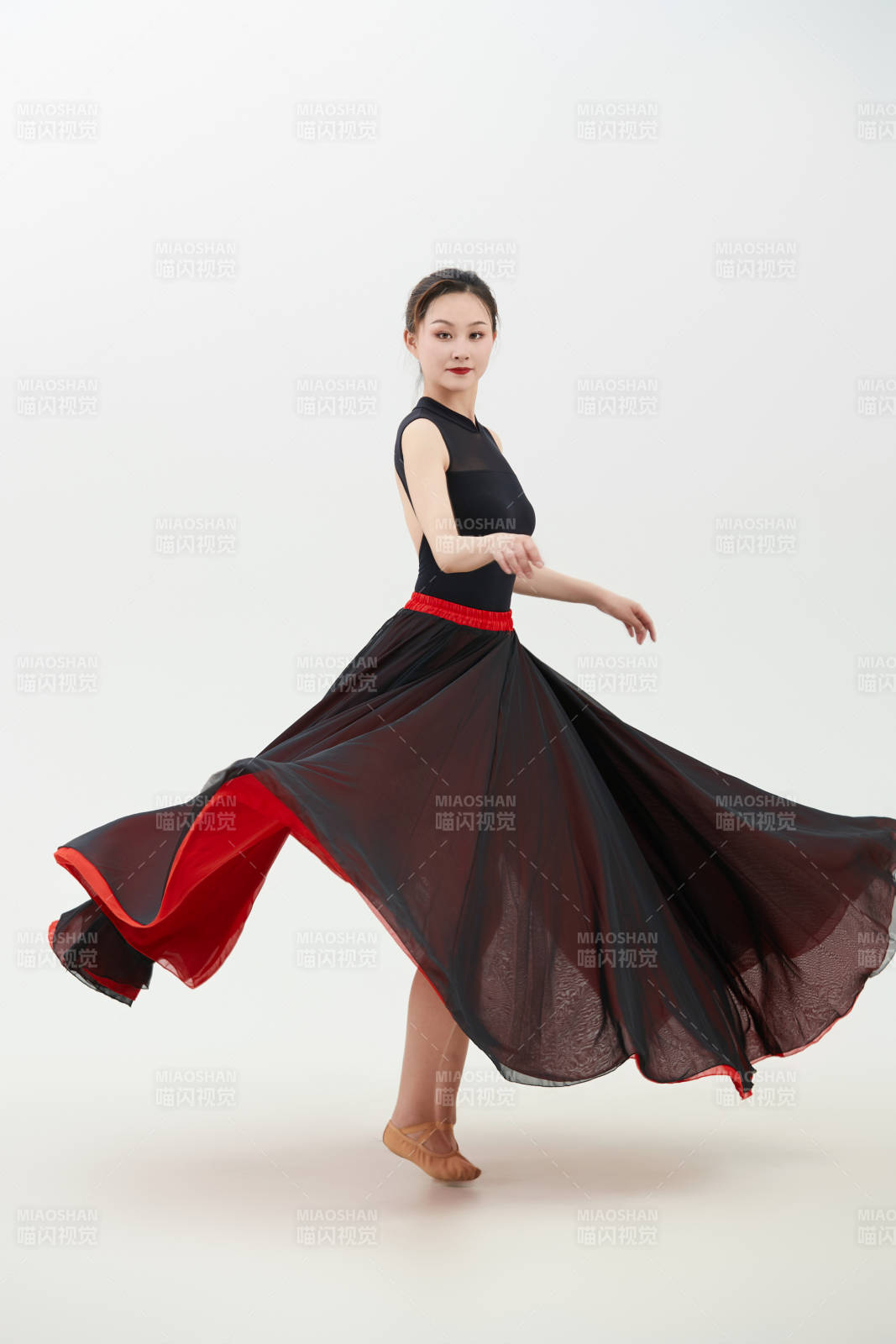 身穿紅黑相間的舞蹈長裙翩翩起舞的少女