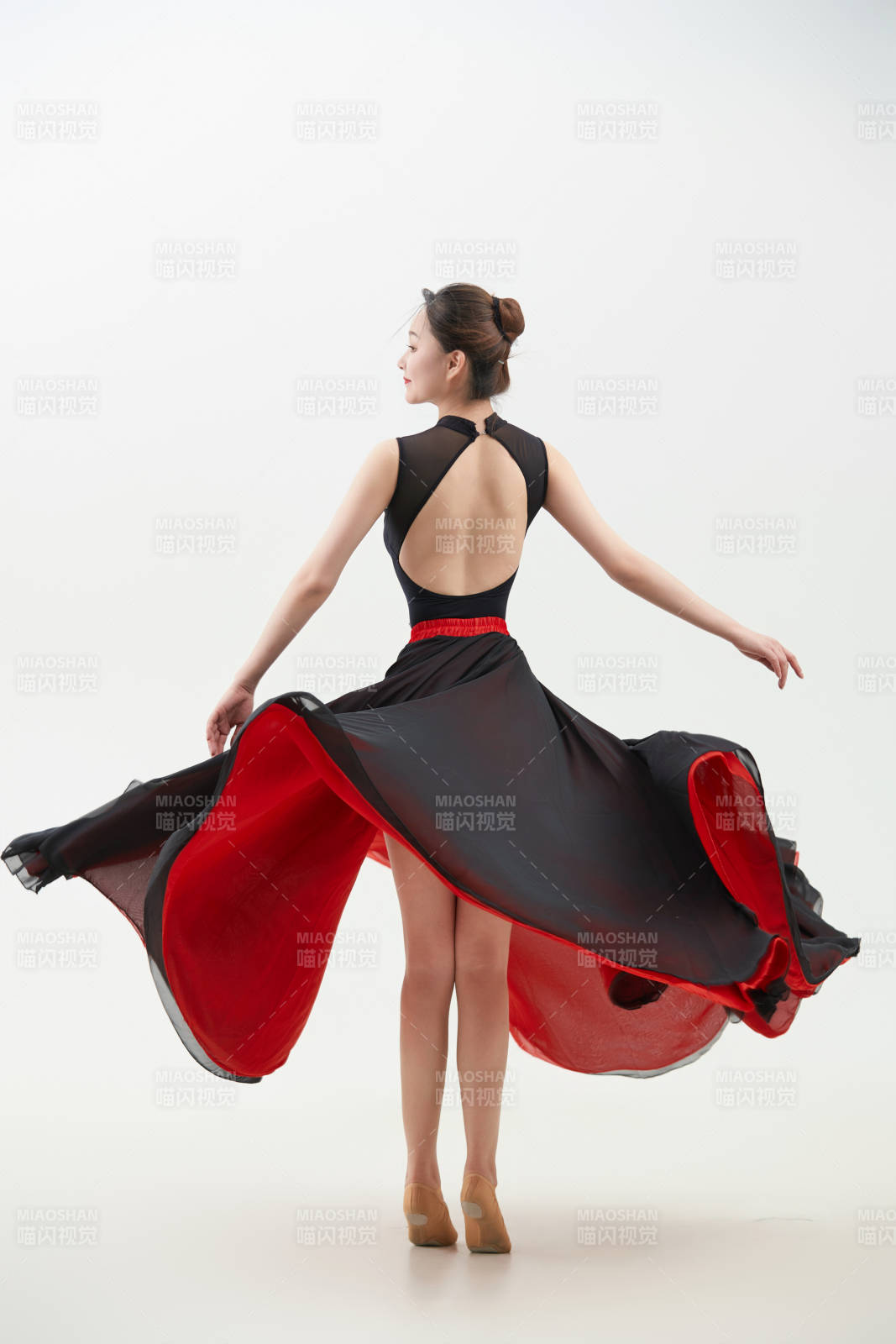 身穿紅黑相間的舞蹈長裙翩翩起舞的少女