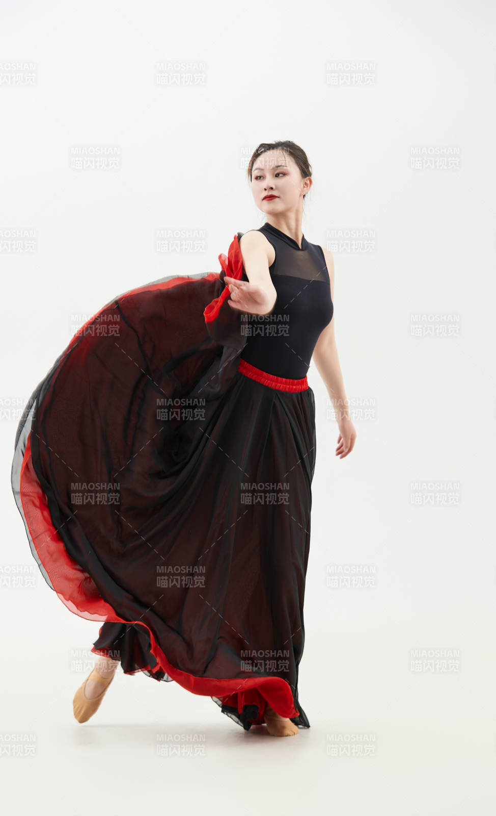 身穿紅黑相間的舞蹈長裙翩翩起舞的少女