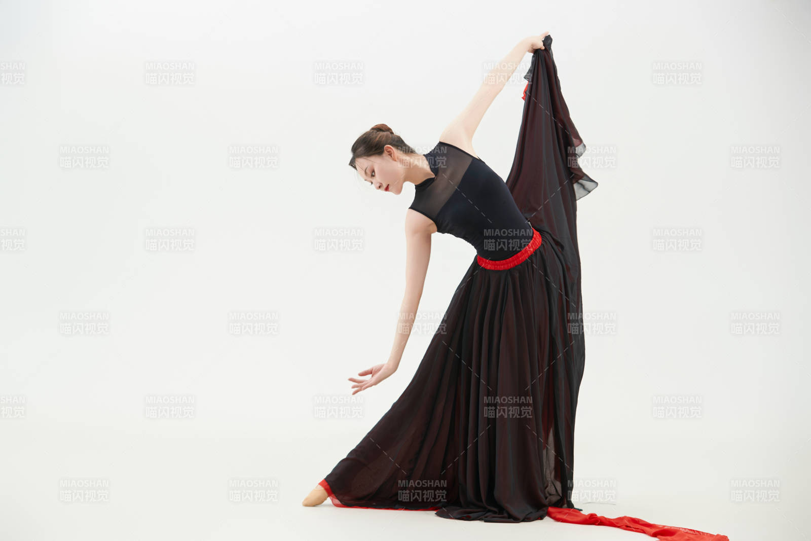 身穿紅黑相間的舞蹈長裙翩翩起舞的少女