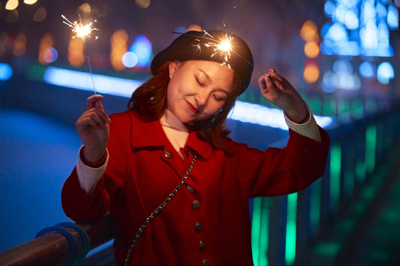 夜晚燃放仙女棒的可爱亚洲少女