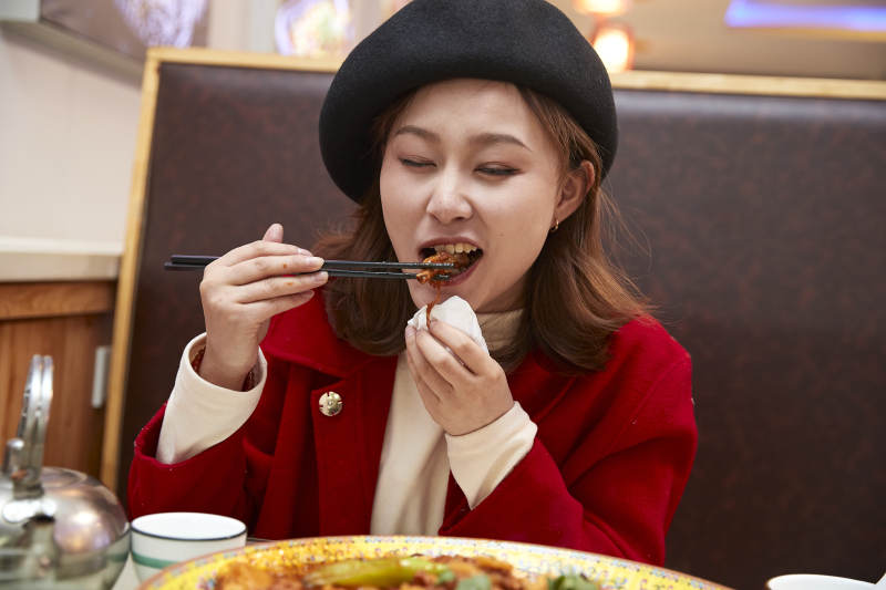 在餐厅吃美味新疆大盘鸡的亚洲少女