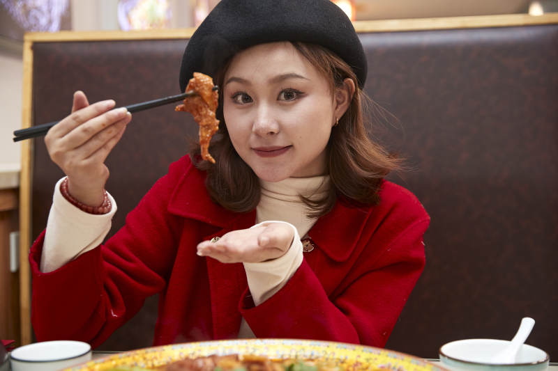 在餐厅吃美味新疆大盘鸡的亚洲少女
