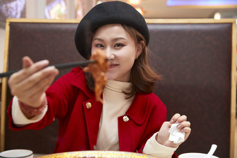 在餐厅吃美味新疆大盘鸡的亚洲少女