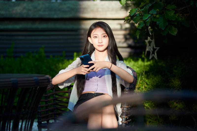 夕阳下在庭院休息拍照的亚洲少女