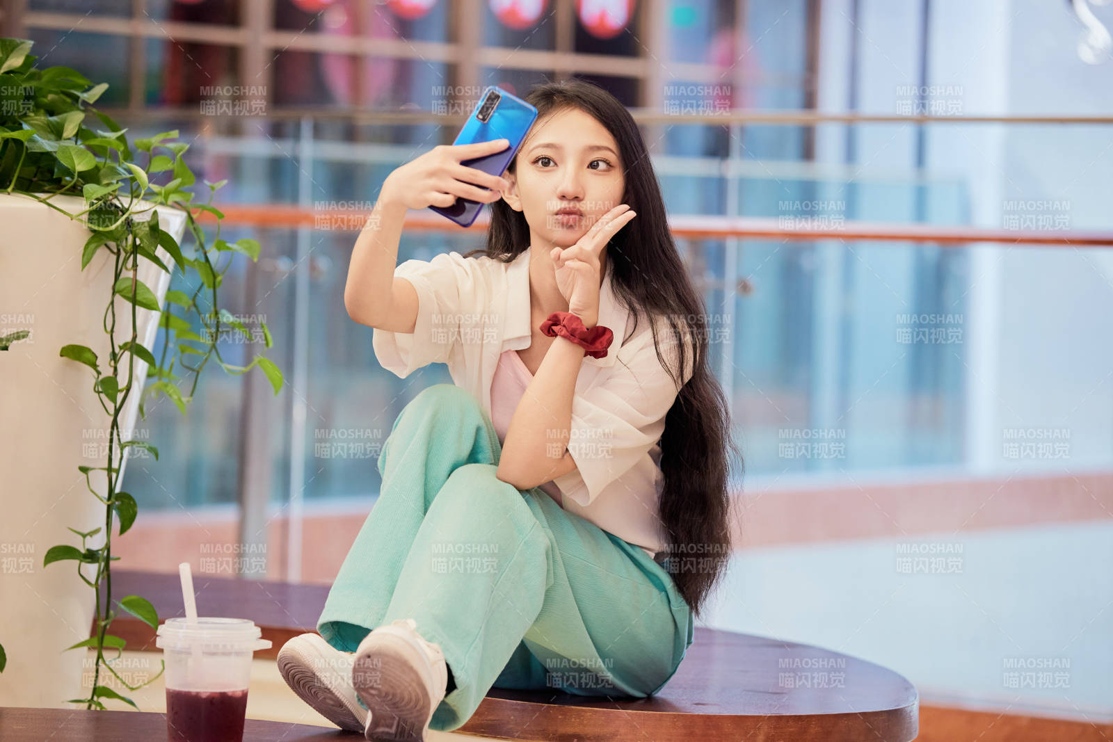 假日在商場休息區用手機自拍的中國少女