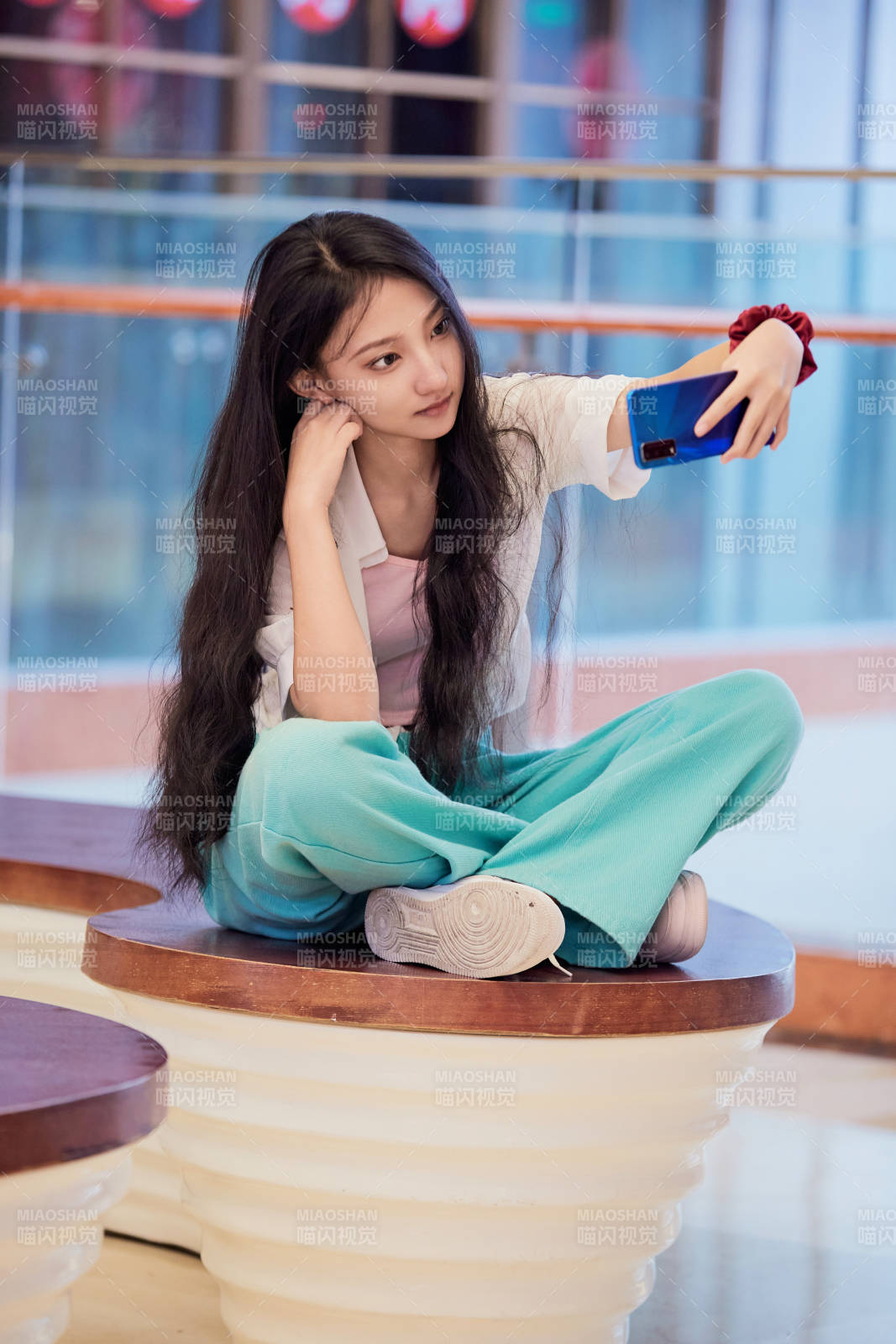 假日在商場休息區用手機自拍的中國少女