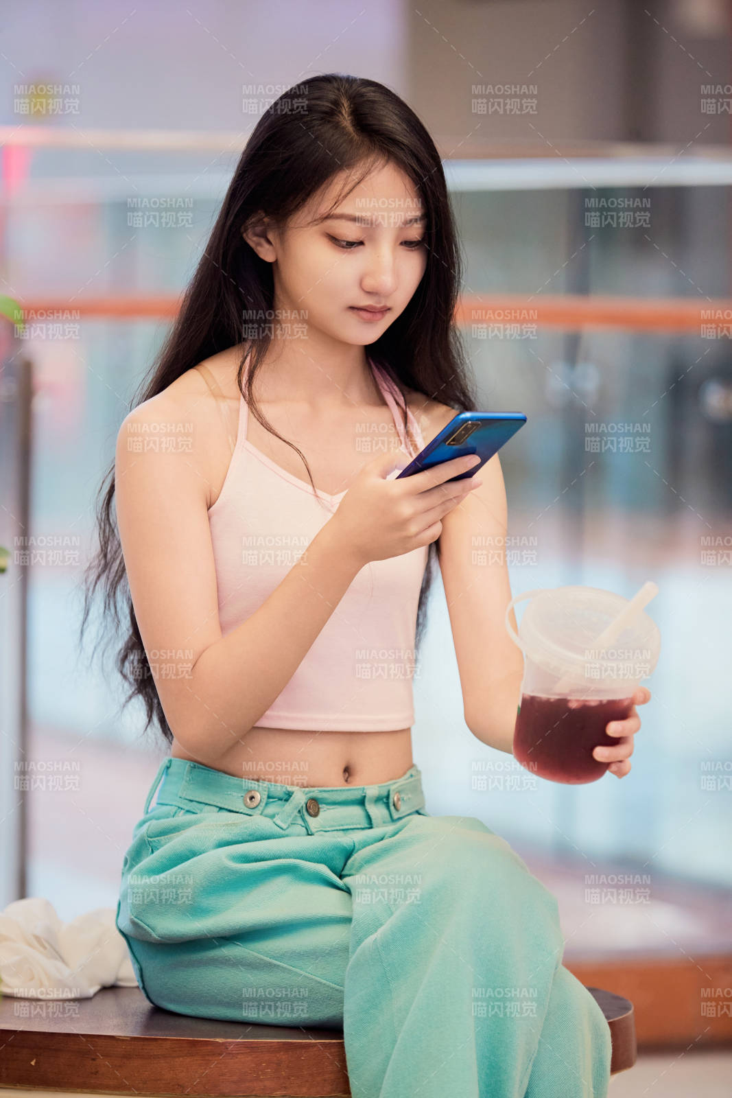 假日在商場休息區(qū)用手機自拍的中國少女