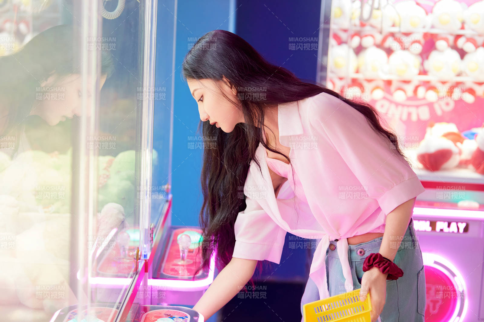 在電子游戲娛樂城玩抓娃娃機的時尚少女