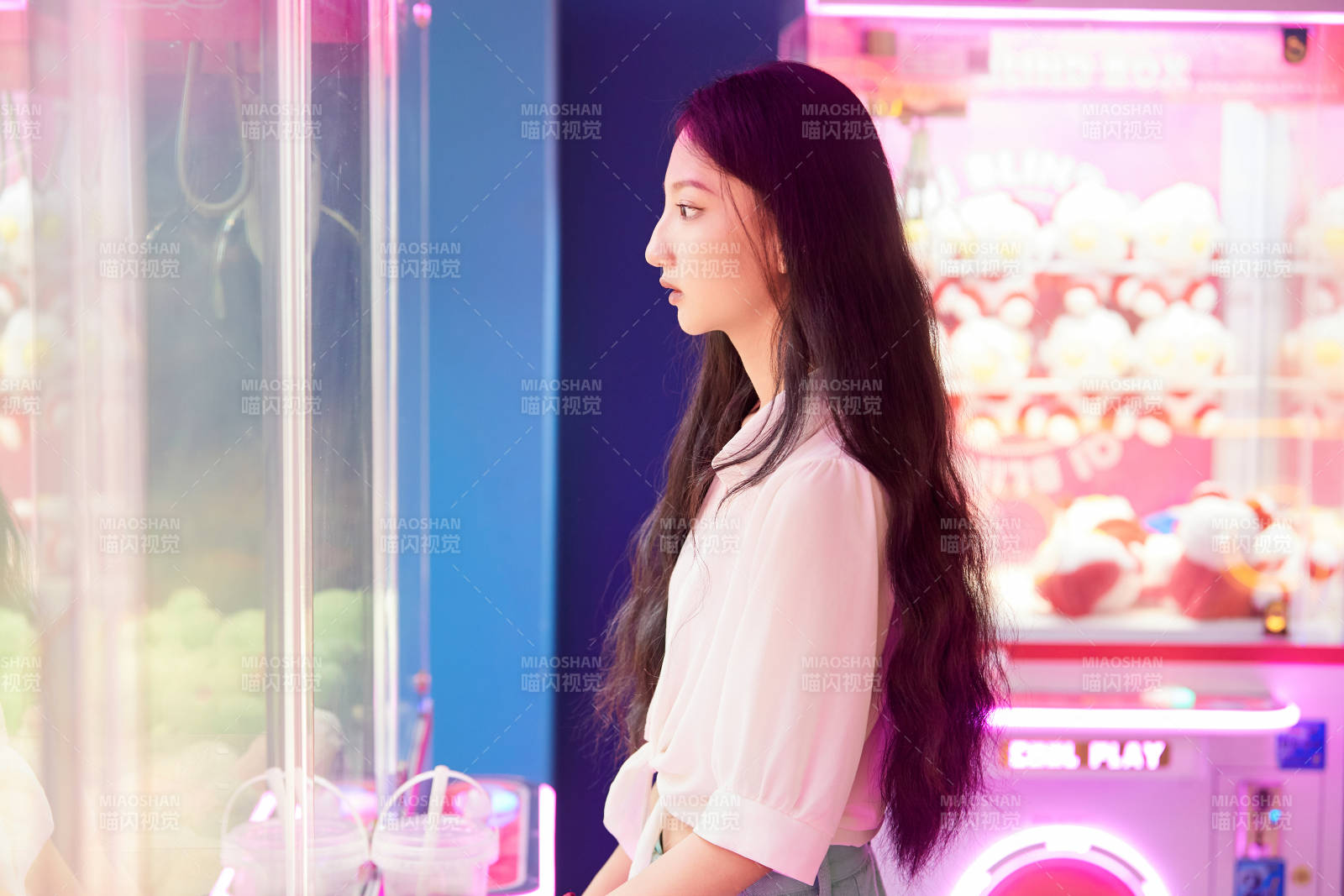 在電子游戲娛樂城玩抓娃娃機的時尚少女