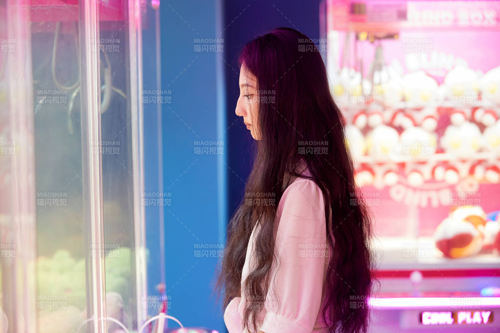 在電子游戲娛樂城玩抓娃娃機的時尚少女