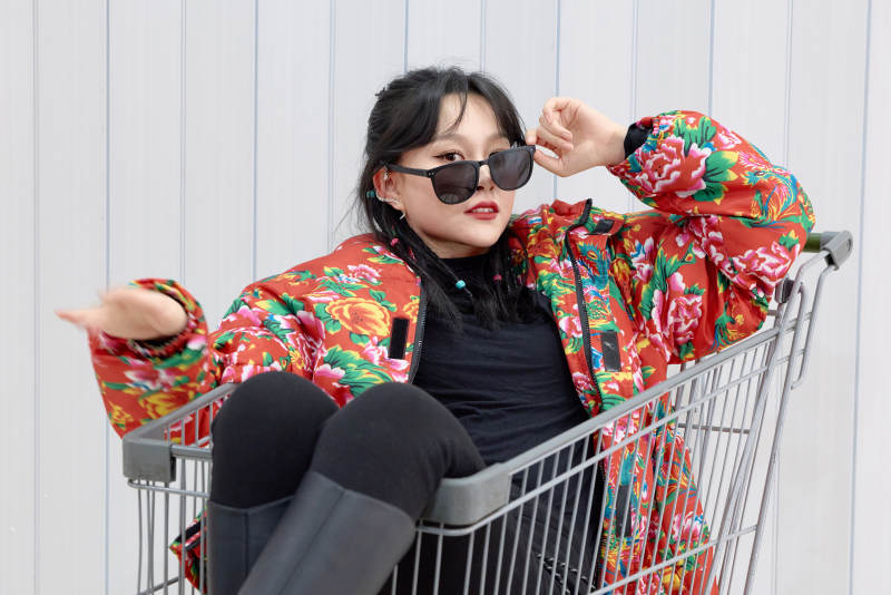 坐在商场超市购物车拍照玩乐的亚洲美女